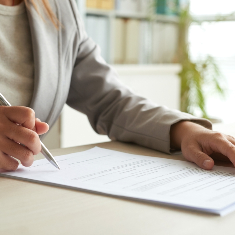 Hands of business entrepreneur signing document on her table